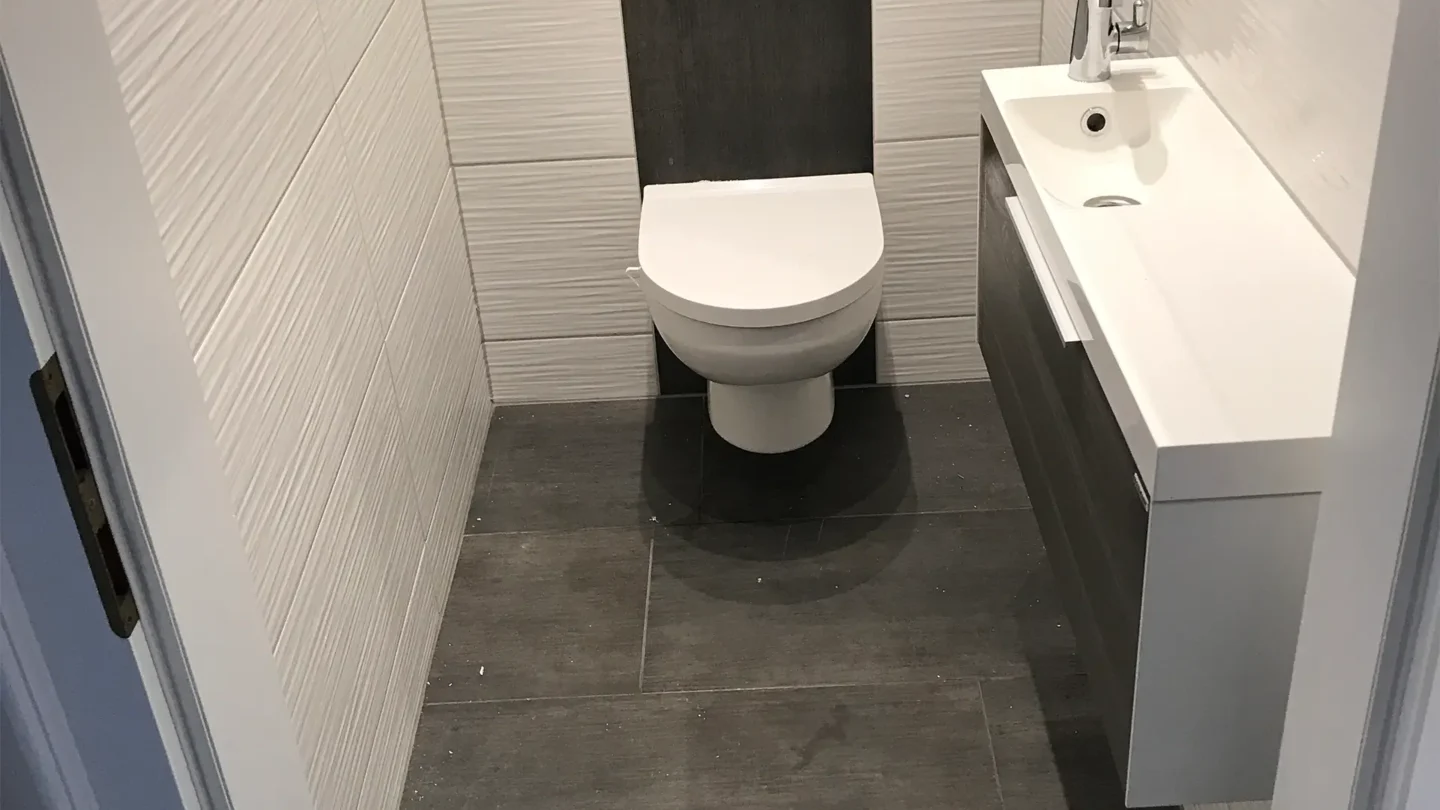 Modernes Gäste-WC mit großformatigen Bodenfliesen und strukturierter Wandgestaltung.