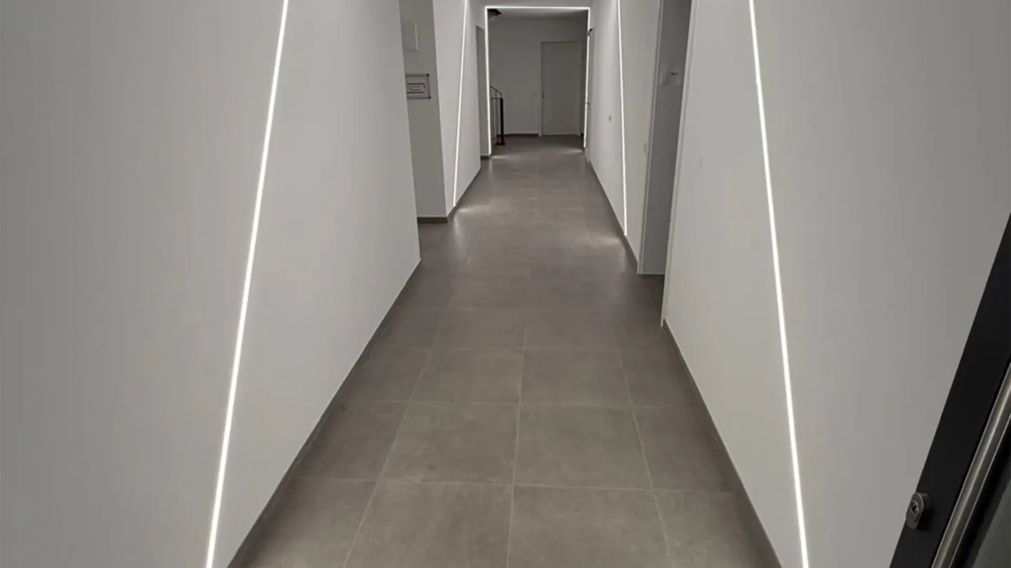 Heller Flur mit großformatigen Bodenfliesen und integrierter LED-Beleuchtung.