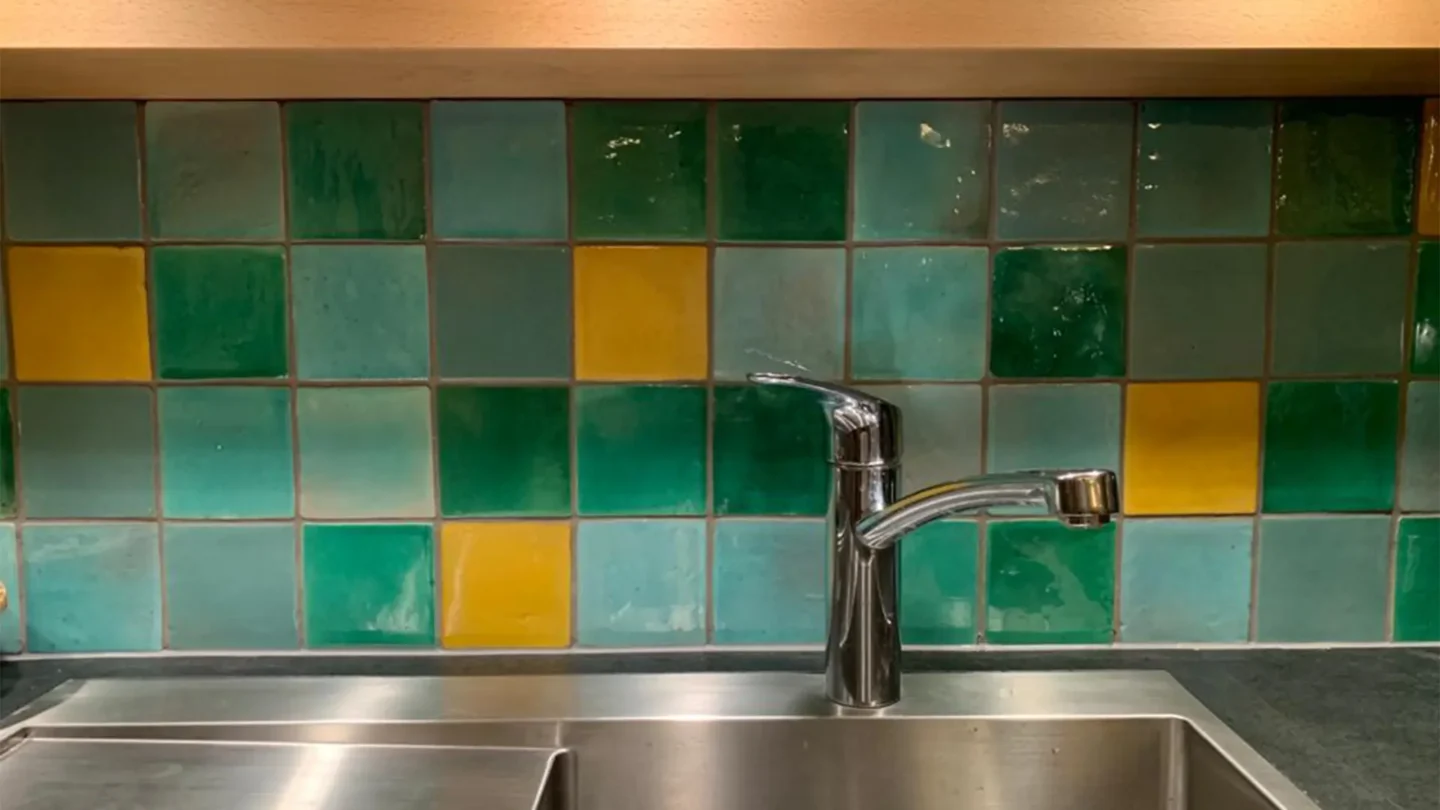 Küchenrückwand mit handgefertigten grünen und gelben Fliesen im individuellen Design.