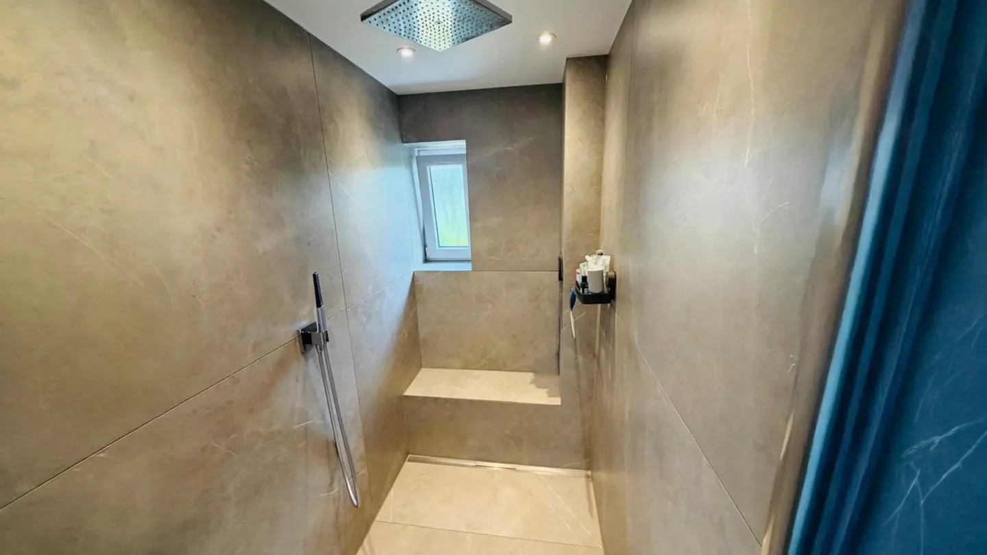 Großzügige Walk-in-Dusche mit großformatigen Fliesen und moderner Regendusche.