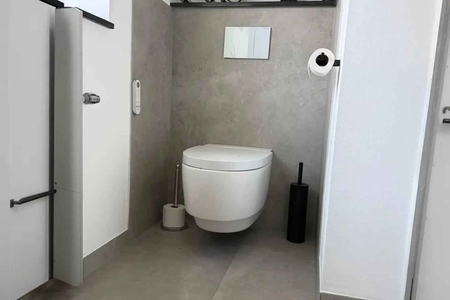 Modernes wandhängendes WC mit großformatigen Feinsteinzeugfliesen in Natursteinoptik.